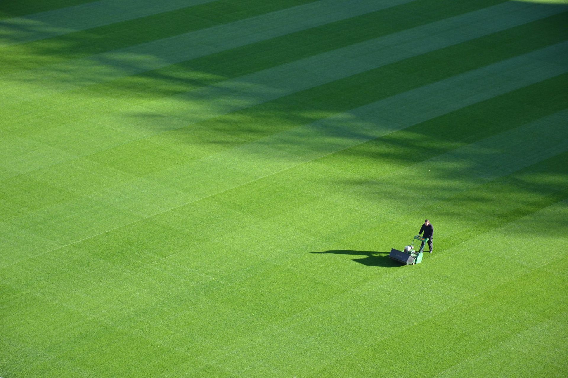 Mower striping a large field of green turf